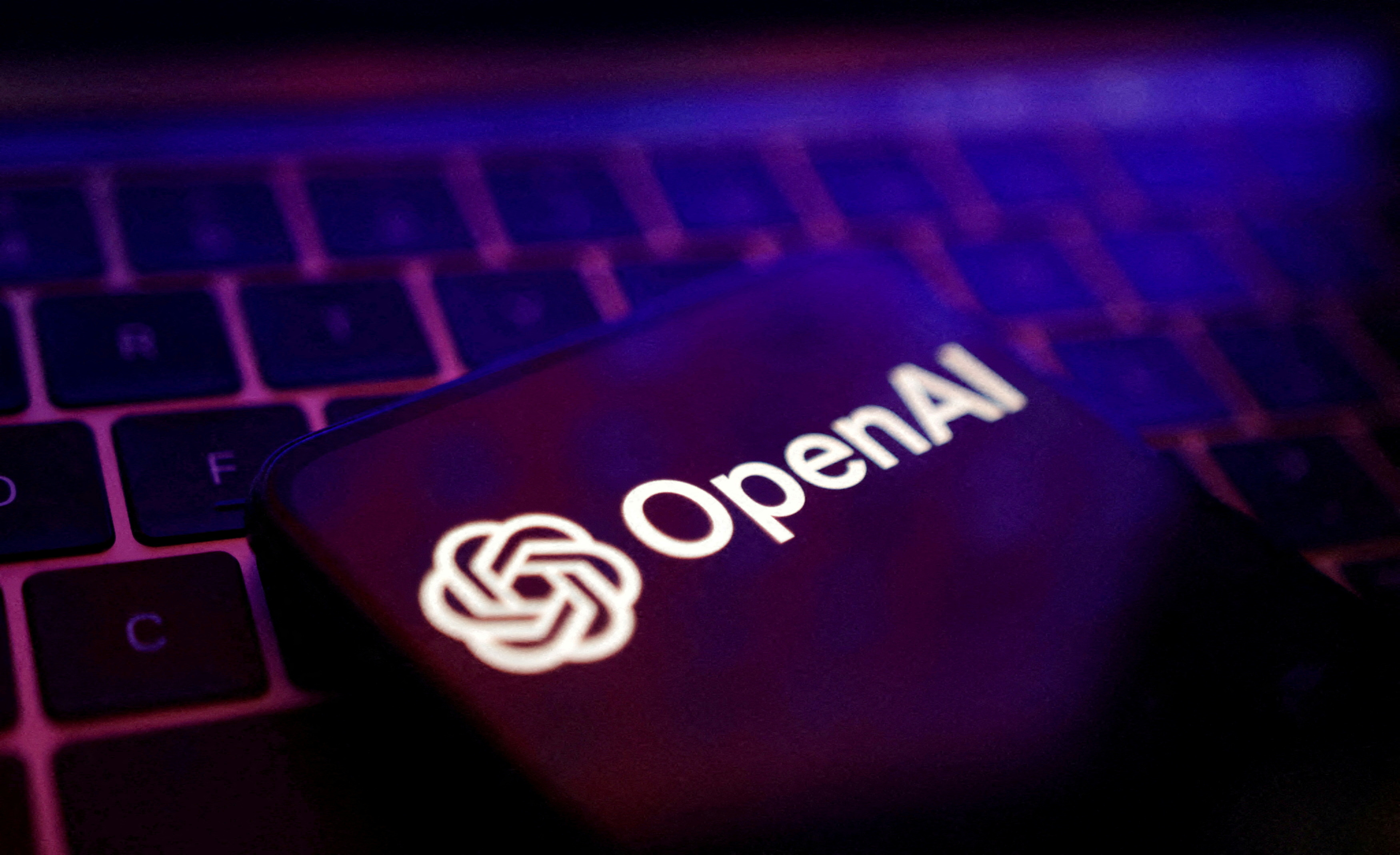 โลโก้ OpenAI บนหน้าจอสมาร์ตโฟนวางอยู่บนแป้นพิมพ์แล็ปท็อป