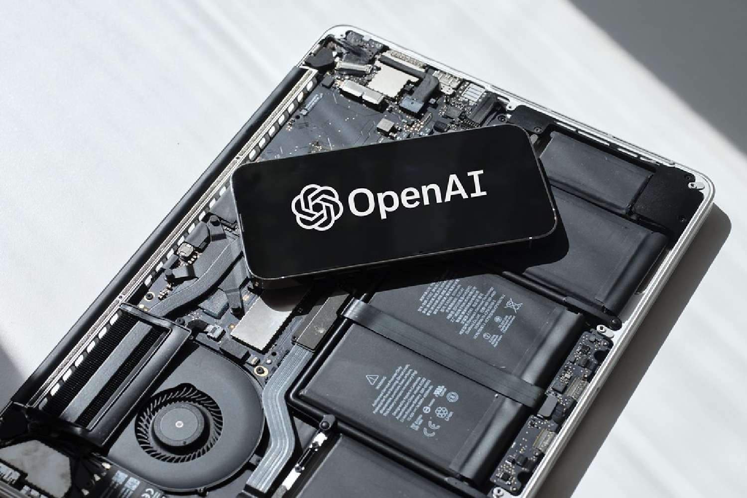 ภาพประกอบโลโก้ OpenAI วางอยู่บนแผงวงจรอิเล็กทรอนิกส์ สื่อถึงฮาร์ดแวร์ AI ที่ OpenAI พัฒนาเอง