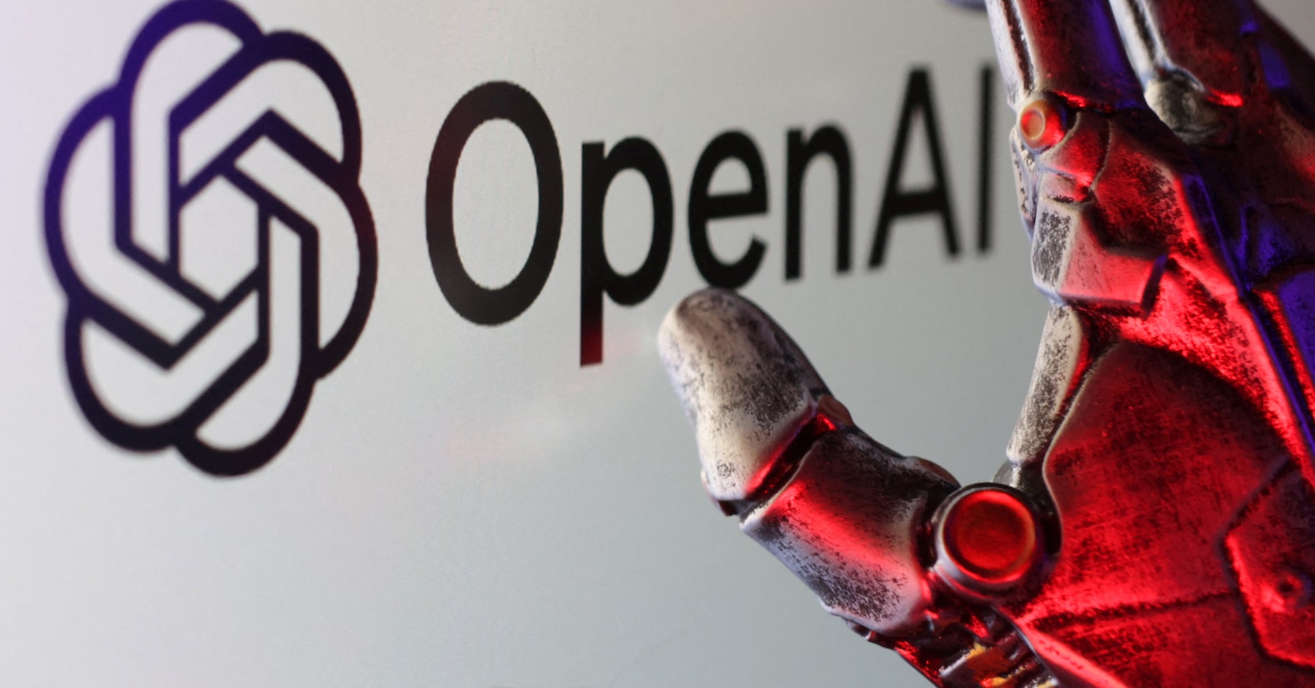 โลโก้ OpenAI พร้อมมือหุ่นยนต์สีแดงยื่นเข้ามาใกล้ สื่อถึงความกังวลเรื่องพฤติกรรมโมเดล AI ที่ควบคุมยาก